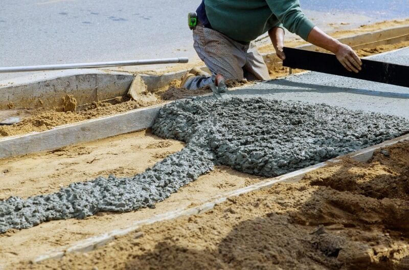 Construction worker creating a sidewalk using a concrete mixer.